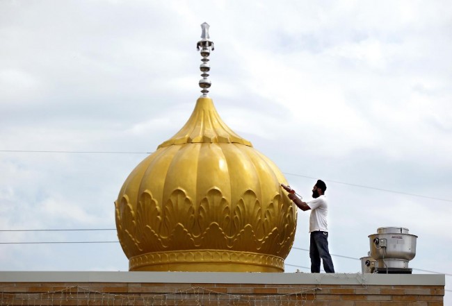 Jaspreet Singh works on caulking the seams in one of seven domes being installed on the roof of the Sikh Temple of Wisconsin in Oak Creek on Wednesday. - Image credit: Mike De Sisti 