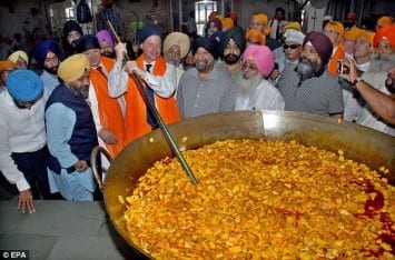 Feeling the heat: Mr Clegg mixes vegetables at a community kitchen during his visit to the Sikh temple 