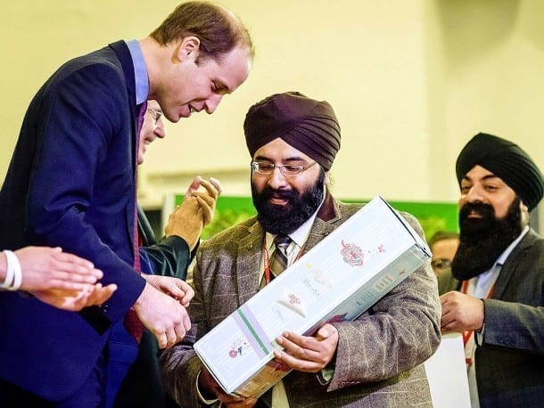 Prince William is handed dolls as gifts for his wife and daughter by Satnam Sagoo and his brother Pally.